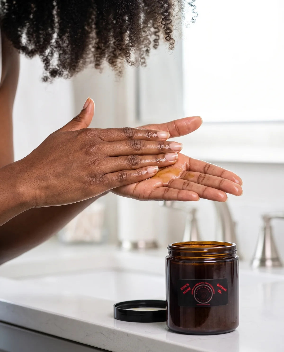 Hands warming a small amount of batana oil